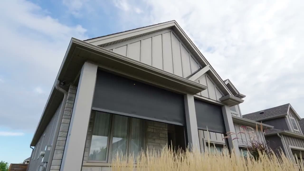 Modern Ontario home at golden hour with retractable screens deployed across a covered patio
