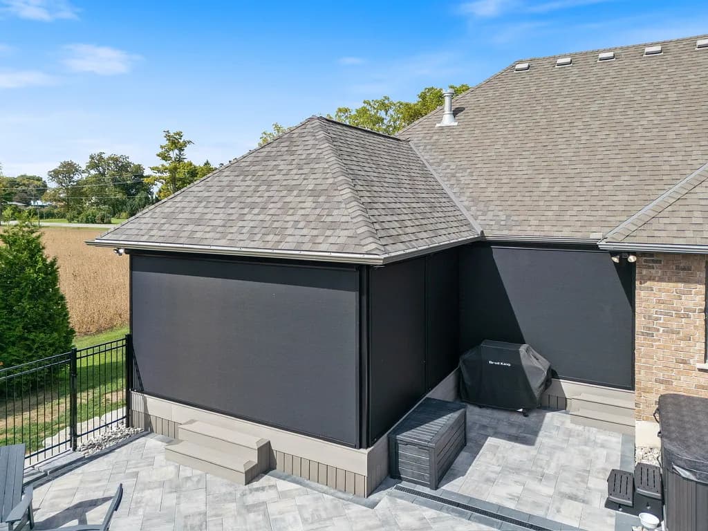 Aerial of corner-deployed black solar mesh on a brick home