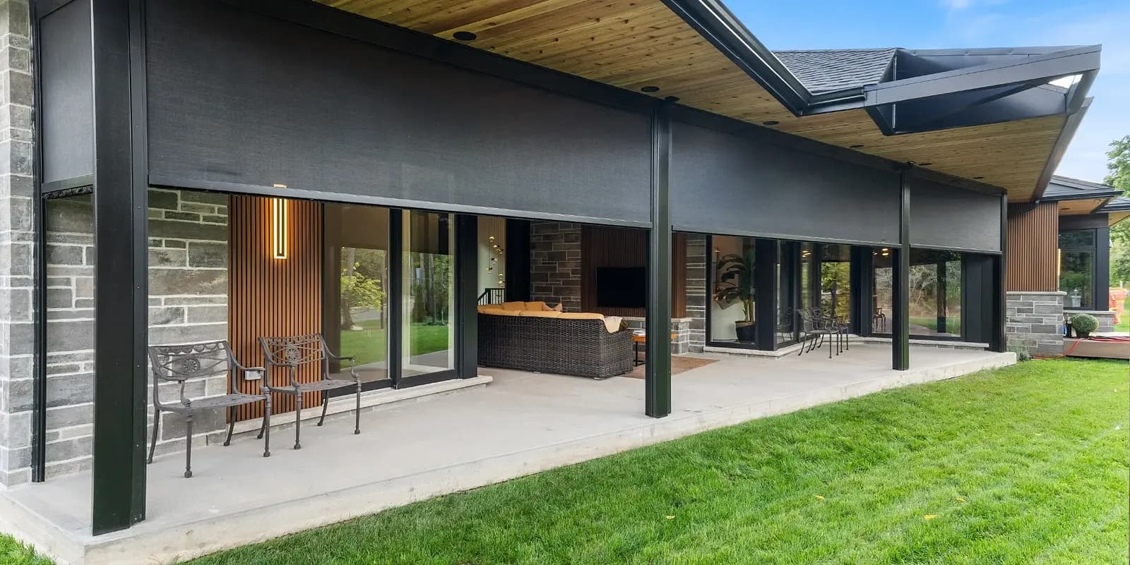 Modern dark home with retractable screens across a wide patio