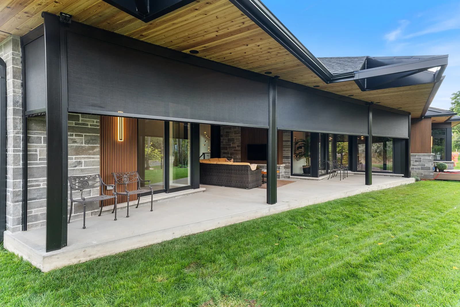 Modern luxury home with deployed dark solar shades on a long covered porch