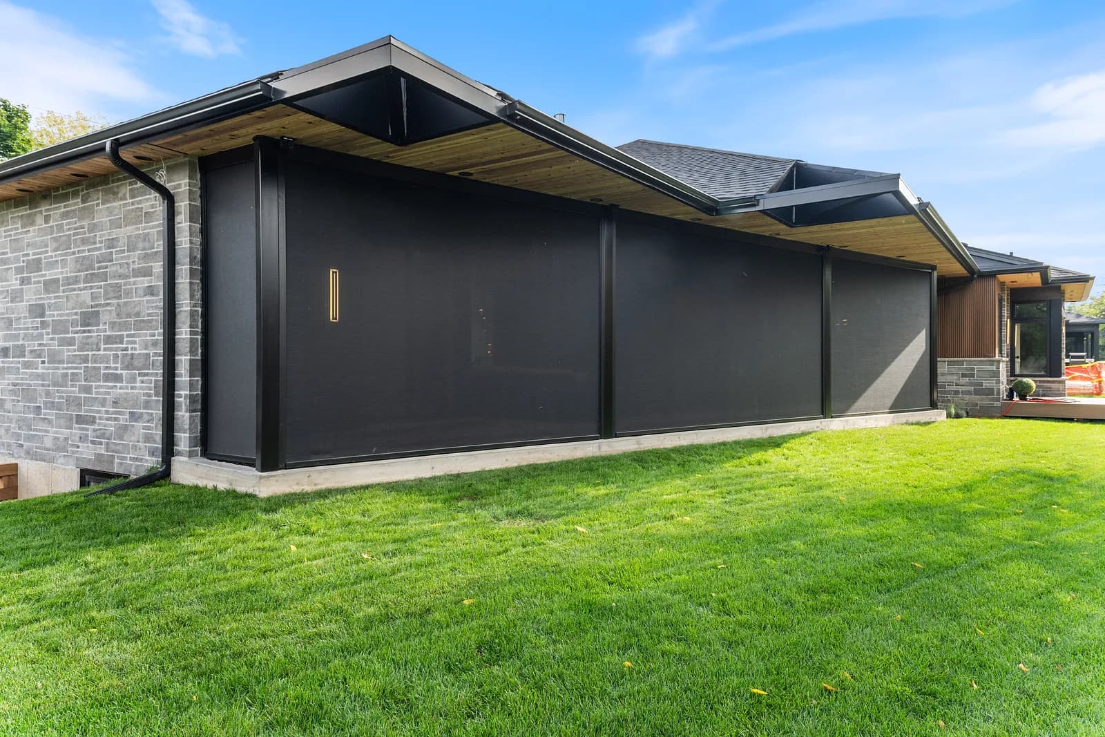 Side angle of a modern luxury home with deployed dark shades