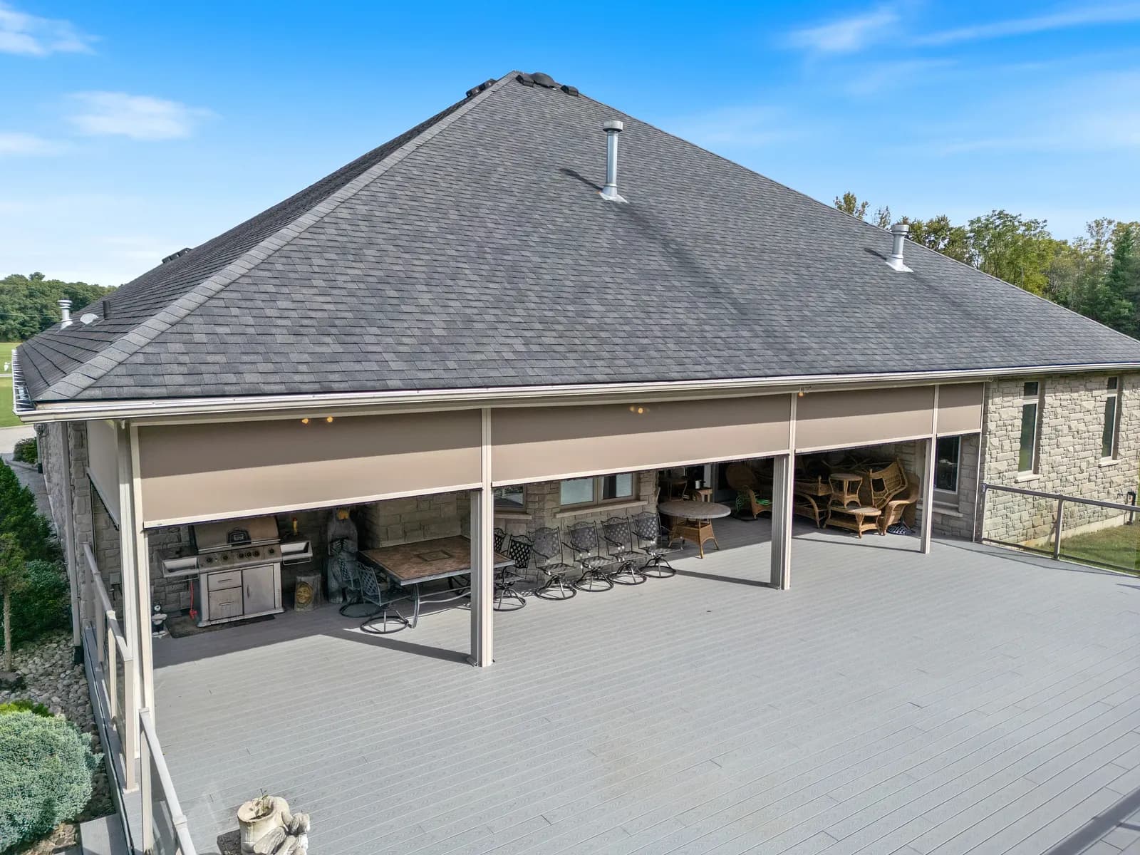 Aerial view of long stone home with multiple solar shades retracted
