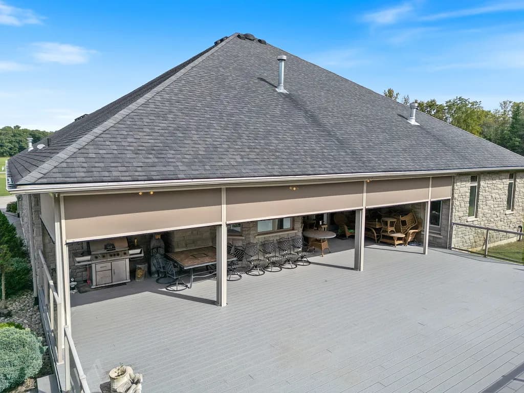 Drone view of stone home with multiple deployed Talius shades
